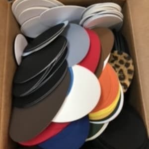 May include: A cardboard box filled with various colored shoe insoles. The insoles are in a variety of colors including black, white, red, blue, brown, and orange. Some insoles have a leopard print design.