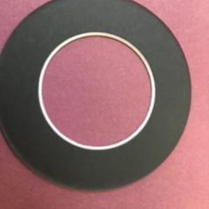 May include: A black and white ring-shaped gasket with a smooth, flat surface.