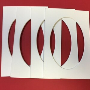 May include: Four white oval-shaped picture frames with a cut-out oval in the center. The frames are stacked on top of each other.