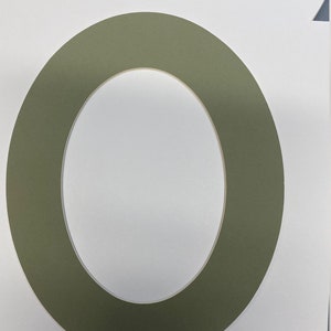 May include: A green oval-shaped mat with a smaller oval-shaped cutout in the center. The mat is made of a thick, sturdy material and has a smooth, even surface.