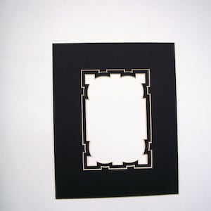 May include: A black picture mat with a decorative, scalloped opening. The mat is rectangular with a white interior border. The background is plain white.