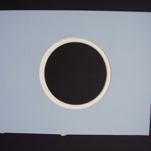 May include: A light blue mat with a white circle cut out in the center. The circle is about 6 inches in diameter.