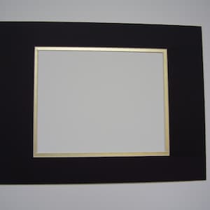 May include: Black mat board with a gold border, creating a picture frame.
