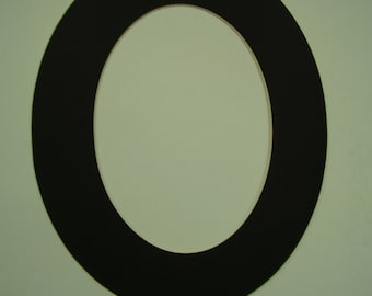 May include: A black oval-shaped object with a white interior, set against a pale green background. The object is a solid, dark color, and the shape is clearly defined. The design is simple and modern.