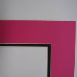 May include: A pink mat board with a black and white mat border. The mat board is used for framing artwork or photographs.