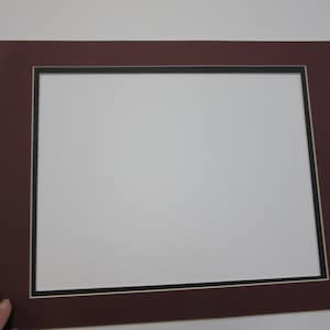 May include: A maroon mat with a black and white double border. The mat is designed to hold a picture or artwork.