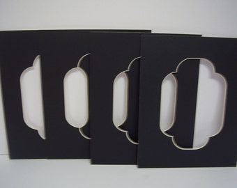 May include: Four black mat boards with a decorative cut-out window in the shape of an oval with a scalloped top and bottom. The mat boards are stacked on top of each other.