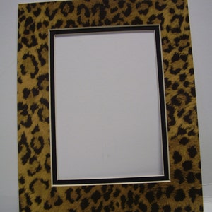 May include: A picture frame with a leopard print border and a black and white inner border. The frame is made of wood and has a matte finish.