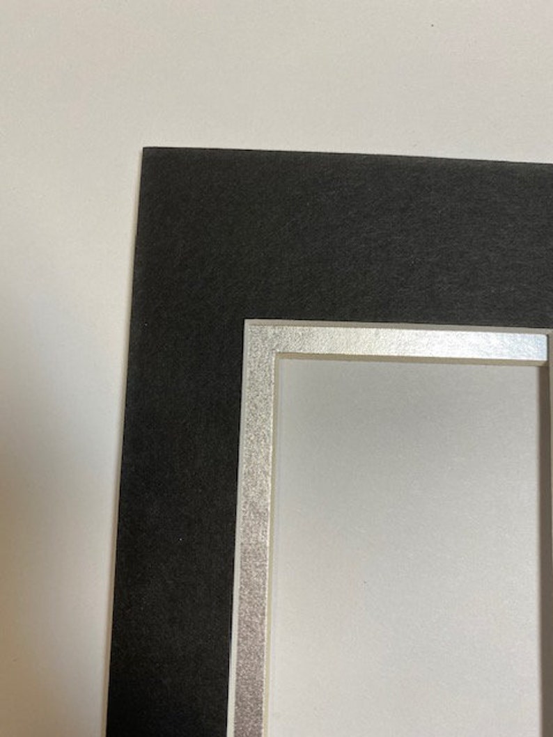 K&ouml;nnte beinhalten: Ein schwarzer Bilderrahmen mit silbernem Rand und wei&szlig;em Innenraum. Der Rahmen dient dazu, ein Foto oder Kunstwerk einzurahmen. Der schwarze Rahmen bietet einen kontrastierenden Rand, w&auml;hrend das Silber einen Hauch von Eleganz verleiht.