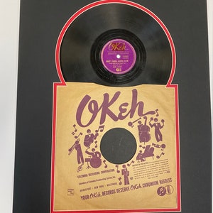 May include: A vintage Okeh record label with a black and white illustration of musicians playing instruments. The label is brown with red and white accents. The text on the label reads "OKeh" and "Your Okeh Records Deserve Okeh Chromium Needles".