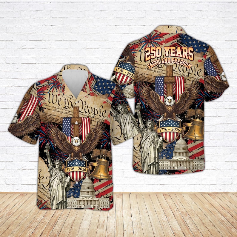 K&ouml;nnte beinhalten: Kurz&auml;rmeliges Hemd mit patriotischem Design. Es zeigt einen Adler, die Freiheitsstatue, die Liberty Bell und das US-Kapitolgeb&auml;ude. Das Hemd tr&auml;gt auch den Text "We the People" und "250 Years Faith and Freedom People".