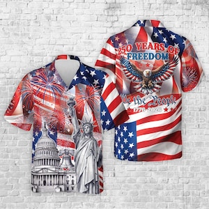 Puede incluir: Una camisa de manga corta con un diseño patriótico. Presenta la bandera estadounidense, fuegos artificiales, la Estatua de la Libertad y el Capitolio. La parte trasera de la camisa muestra un águila y el texto "250 Years of Freedom".