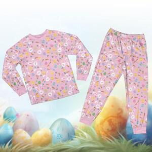May include: Pink pajama set with a repeating pattern of white bunnies, carrots, and Easter eggs. The long-sleeved top and pants have pink cuffs and a light blue background.