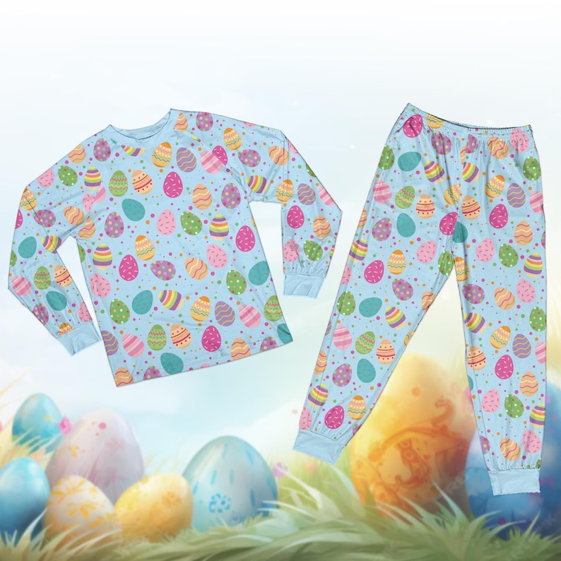 May include: A light blue pajama set featuring a repeating pattern of colorful Easter eggs. The long-sleeved top and pants have a matching design with eggs in various colors, including pink, yellow, green, and blue. The pajama set is designed for comfort and seasonal celebrations.