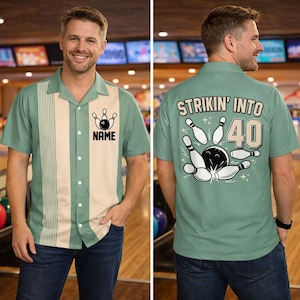 Könnte beinhalten: Hellgrünes Bowlinghemd mit cremefarbenem Einsatz auf der Vorderseite. Das Hemd zeigt eine Bowlingkegel- und Kugelgrafik mit dem Wort "NAME" darunter. Auf der Rückseite des Hemdes steht "STRIKIN' INTO 40" mit einer Bowlinggrafik.