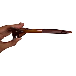 May include: Brown and tan sunglasses with a curved frame and dark brown arms. The sunglasses have a sleek, modern design, suitable for outdoor activities. The lenses are not visible in this image.