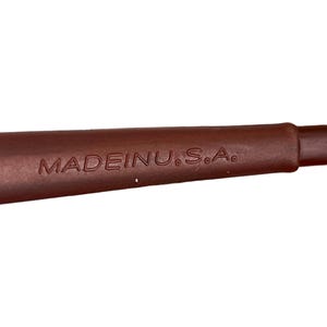 May include: Close-up of a brown object with the text "MADE IN U.S.A." embossed on its surface. The object appears to be a handle or part of a larger tool or utensil, with a smooth, rounded shape.