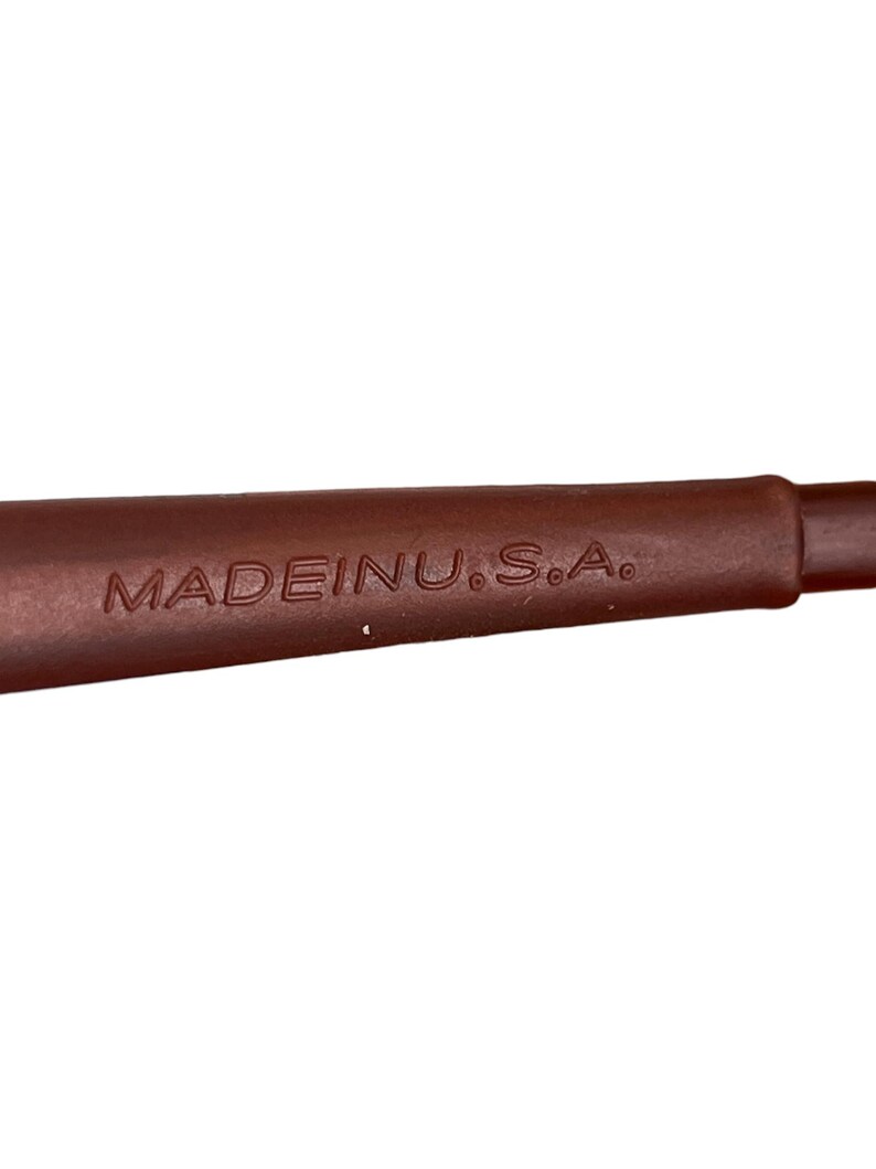 May include: Close-up of a brown object with the text "MADE IN U.S.A." embossed on its surface. The object appears to be a handle or part of a larger tool or utensil, with a smooth, rounded shape.