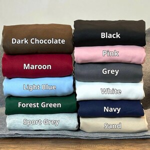 May include: A stack of folded fabric in various colors, including dark chocolate, maroon, light blue, forest green, and sport grey. The stack also includes black, pink, grey, white, navy, and sand-colored fabrics. Each color is labeled with its name in white text.