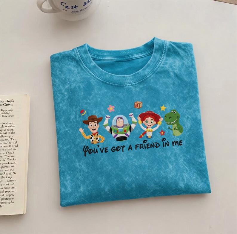 Puede incluir: Camiseta turquesa con un dise&ntilde;o de personajes de Toy Story: Woody, Buzz Lightyear, Jessie y Rex. El texto "You've Got a Friend in Me" est&aacute; debajo. La camiseta tiene cuello redondo y un aspecto descolorido.