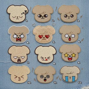 May include: A collection of twelve embroidered patches, each featuring a light brown dog-like character with different facial expressions. The patches are numbered and arranged on a blue fabric background. The expressions range from sleeping to surprised.