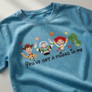 Puede incluir: Camiseta azul claro con personajes de Toy Story. La camiseta tiene un dise&ntilde;o de Woody, Buzz Lightyear, Jessie y Rex, con el texto "You've got a friend in me".