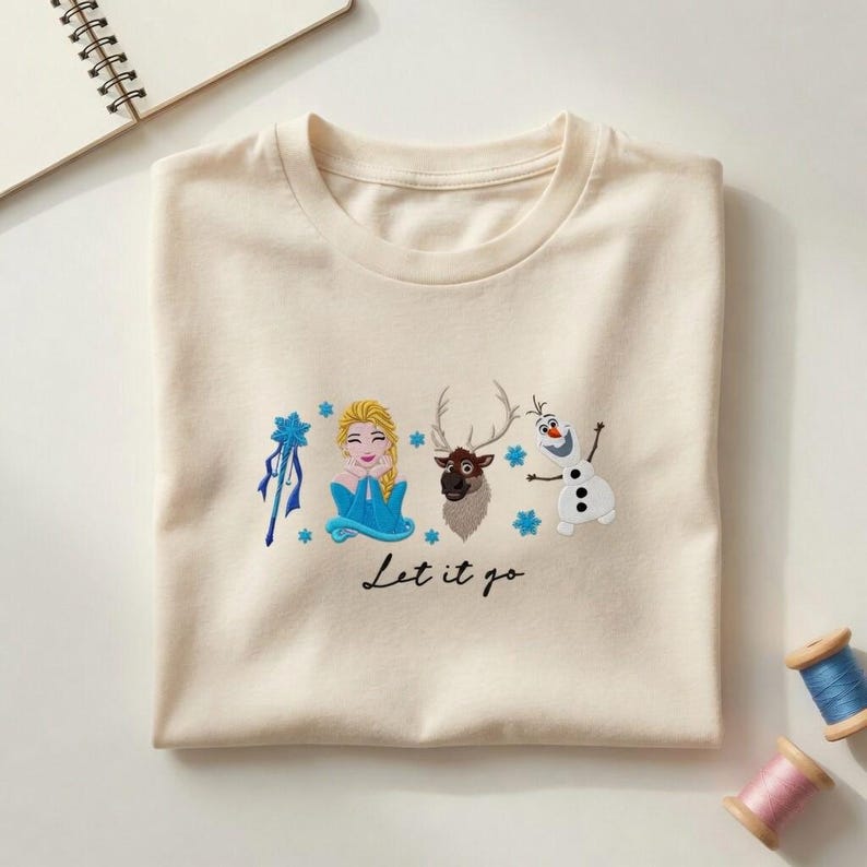 Puede incluir: Camiseta color crema con bordados de personajes de la pel&iacute;cula Frozen. El dise&ntilde;o incluye a Elsa, Sven, Olaf y la frase "Let it go". Acentos de copos de nieve azules completan el dise&ntilde;o.