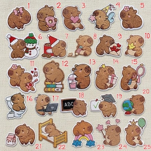 May include: A selection of embroidered capybara patches. The capybaras are depicted in different scenarios, such as holding a heart, a gift, or a star. Some wear a party hat or a crown. Others are shown with a laptop, books, and a globe.