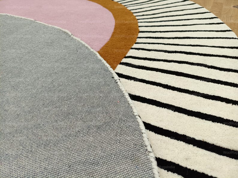 Pu&ograve; includere: Primo piano di un tappeto moderno con un design geometrico. Il tappeto presenta una combinazione di colori, tra cui grigio, rosa, marrone e bianco. Il tappeto ha strisce nere e una forma curva.