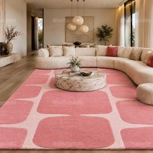 May include: A large rectangular area rug featuring a repeating geometric pattern of soft pink rounded squares separated by a light cream-colored grid. The rug has a dense, plush texture and covers a significant portion of the wooden floor space.