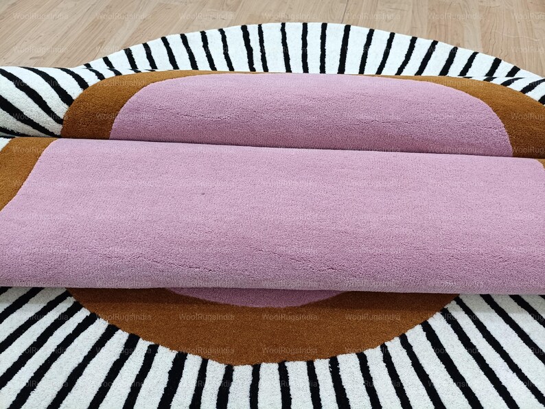 Pu&ograve; includere: Tappeto arrotolato con un centro rosa, un bordo marrone e un motivo a strisce bianche e nere. Il tappeto &egrave; realizzato in un materiale morbido e strutturato, ideale per l'arredamento della casa e misura circa 150 cm di diametro.