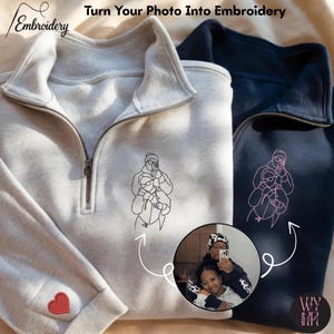 May include: Two quarter-zip sweatshirts, one light gray and one navy blue, with custom embroidery. The light gray sweatshirt has a red heart on the cuff. The text "Turn Your Photo Into Embroidery" is visible.