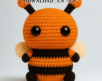Puede incluir: Un peluche de abeja de ganchillo en naranja y negro, con grandes ojos negros y pequeñas antenas. La abeja tiene alas de color crema y está hecha con hilo texturizado. El texto en la parte superior dice "PDF CROCHET PATTERN - INSTANT DOWNLOAD | EN + FR".