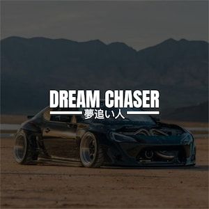 May include: A black sports car with the text "DREAM CHASER" and Japanese characters. The car is parked on a dirt surface with mountains in the background. The car's hood is open, revealing the engine.