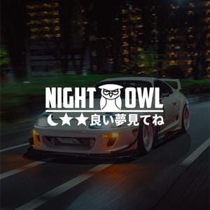 Puede incluir: Coche deportivo blanco con el texto "NIGHT OWL" y un gráfico de búho. Debajo, estrellas, una luna creciente y texto japonés. El coche circula por una carretera de noche, con luces de la ciudad al fondo.