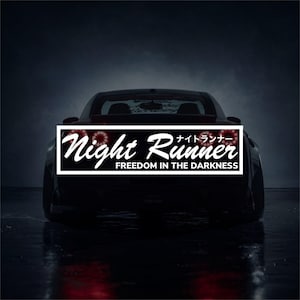 May include: Black car with a white rectangular sticker on the back. The sticker reads "Night Runner" in a stylized font, with Japanese characters and the phrase "Freedom in the Darkness" below.