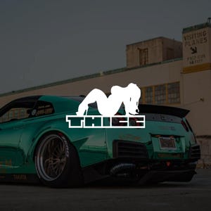 Può includere: Un'auto sportiva verde acqua con uno spoiler nero e una grafica bianca di una persona e la parola "THIEF". L'auto ha pneumatici neri e un sistema di scarico personalizzato. Lo sfondo include un edificio con un cartello che dice "VISITING PLANES".