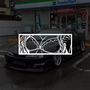 Peut inclure: Un autocollant en vinyle blanc présentant un graphisme au trait stylisé d'un soutien-gorge écarté par deux mains. Le motif est présenté dans un cadre rectangulaire et est affiché sur le capot d'une voiture de sport noire garée devant un magasin.