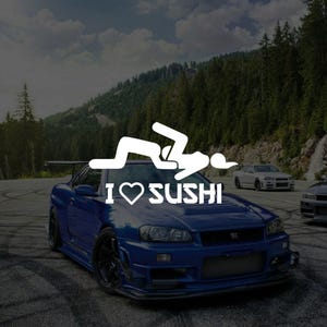 May include: A blue sports car with the text "I ♥ SUSHI" and a white graphic of a person. The car is parked on a paved road with other cars in the background, and a mountain and trees.