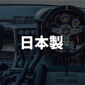 May include: Interior view of a car's dashboard, featuring a steering wheel, gauges, and gear shift. The text "Made in Japan" is prominently displayed in white. The overall aesthetic suggests a focus on automotive design and craftsmanship.