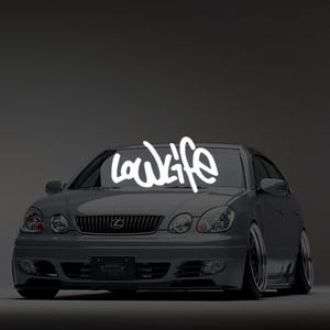 May include: A gray Lexus sedan with the word "lowlife" in white script across the windshield. The car has custom wheels and a lowered suspension, giving it a sporty appearance. The background is a dark gray gradient.