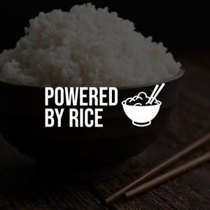 May include: A dark bowl filled with fluffy white rice, with the text "POWERED BY RICE" in white. A small white graphic of a rice bowl with chopsticks is to the right of the text. Two chopsticks rest on a wooden surface.