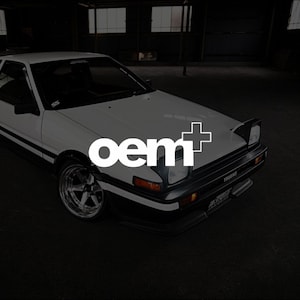 May include: A white sports car with black accents and the text "OEM+" in white. The car has a sleek design with a low profile, black headlights, and chrome rims. The car is parked in a dark garage.