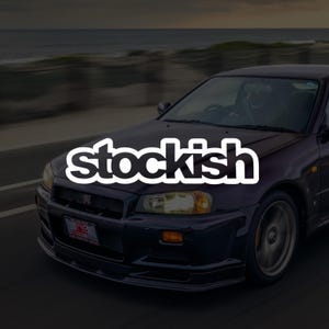 May include: A dark purple sports car driving on a road with the word stockish written in large white letters across the centre of the image. The vehicle features a front grille with a GT emblem, amber turn signals, and a number plate.