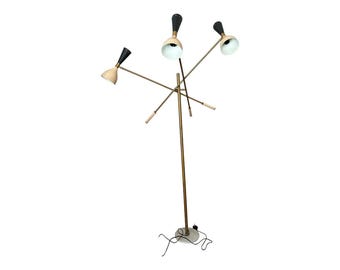 May include: A mid-century modern floor lamp with three adjustable light heads. The lamp features a brass-colored pole and arms, with black and cream-colored shades. The base is a round, marble-like material.
