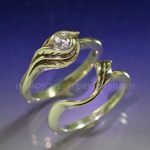 May include: A pair of silver wedding bands with a leaf design. The top band features a single round diamond.