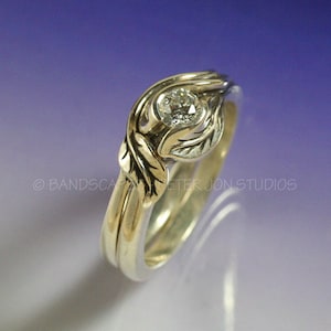 May include: A silver and gold engagement ring with a diamond set in a leaf design. The ring is made of two bands, one silver and one gold, that are intertwined.
