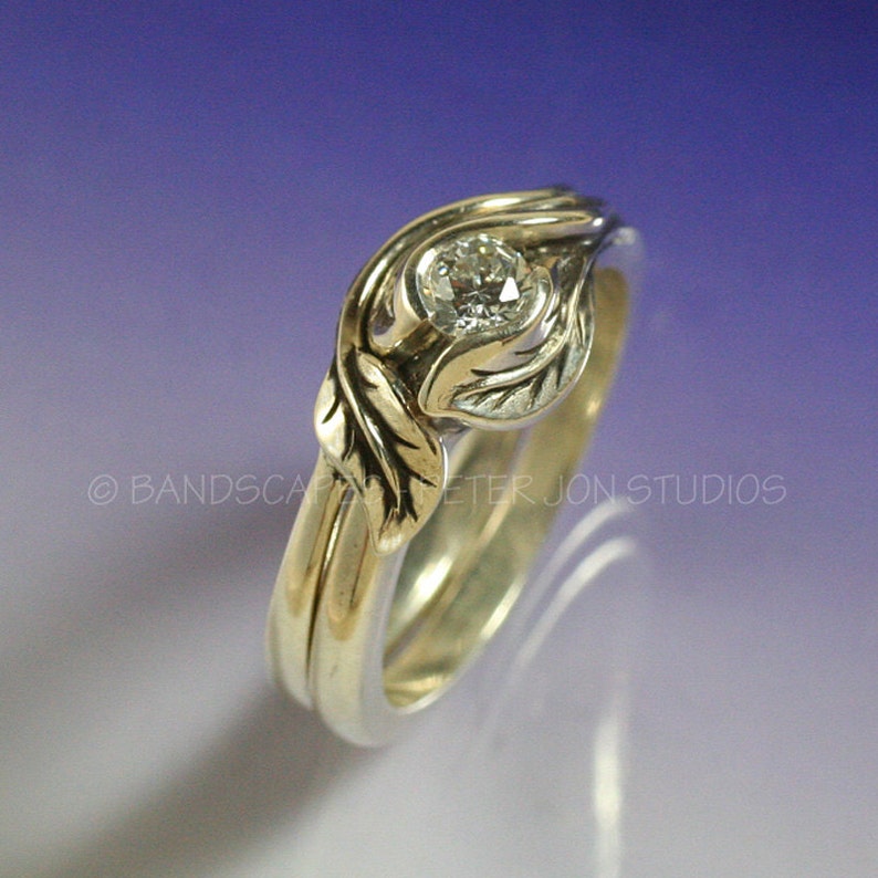 May include: A silver and gold engagement ring with a diamond set in a leaf design. The ring is made of two bands, one silver and one gold, that are intertwined.