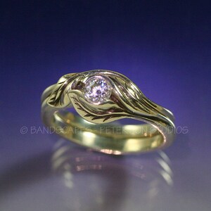 May include: A gold ring with a single round diamond set in a leaf design. The ring is made of two bands, one of which is twisted around the other.