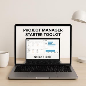 May include: A silver laptop displays a "PROJECT MANAGER STARTER TOOLKIT" on its screen. The screen shows a project management template with data charts and the text "Notion + Excel". A white mug and a desk lamp are visible on the wooden desk.